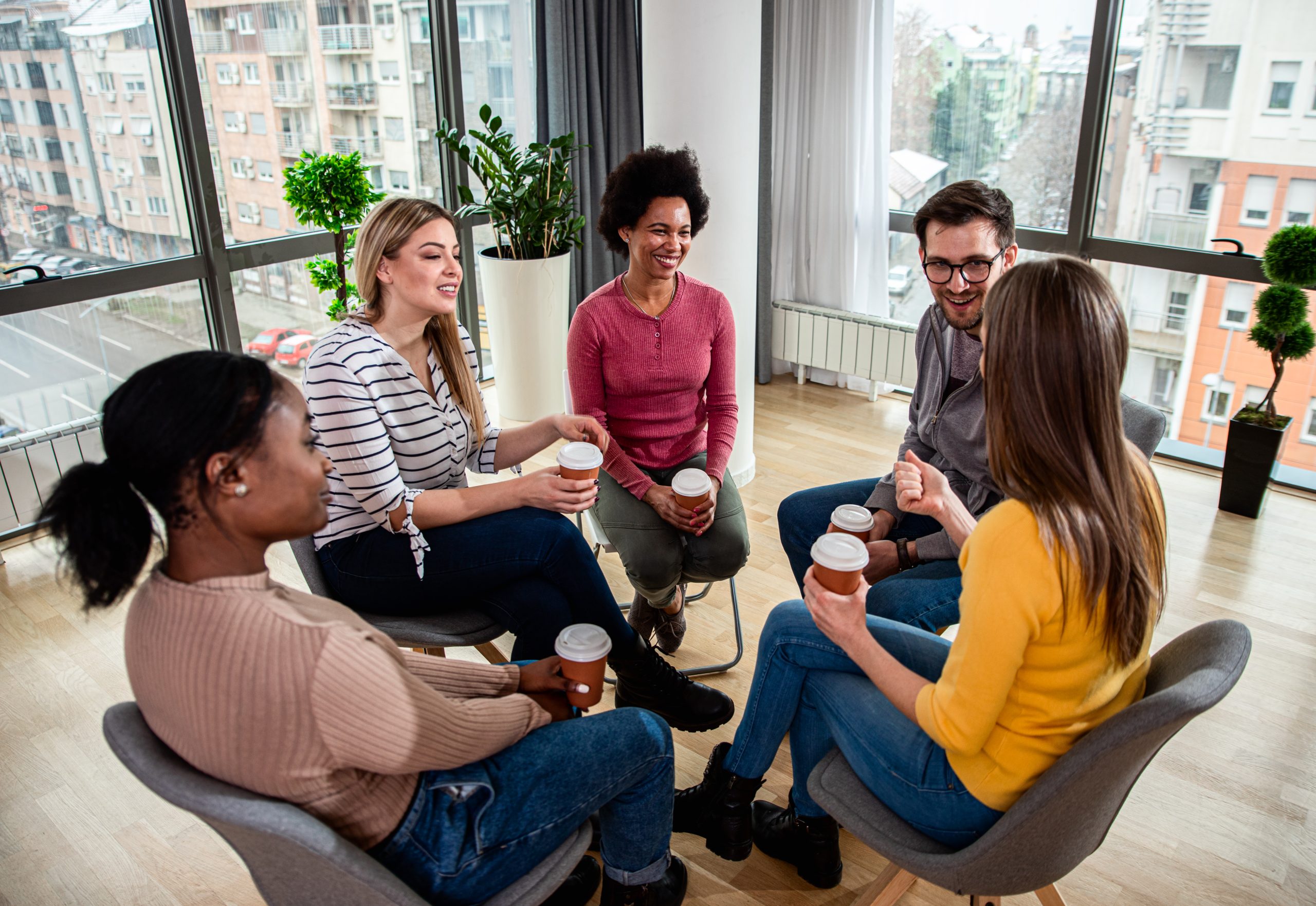 Diverse group of people sitting in circle in group therapy sessi